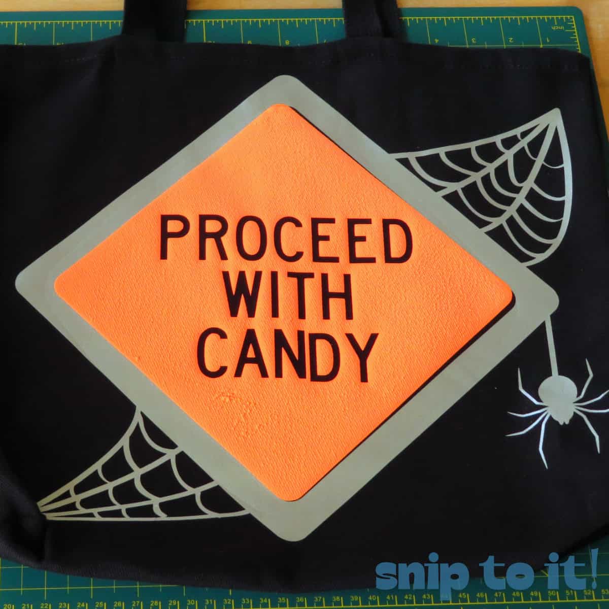 closeup of a trick or treat bag decorated with a mock road sign saying Proceed with Candy in orange puff and reflective htv