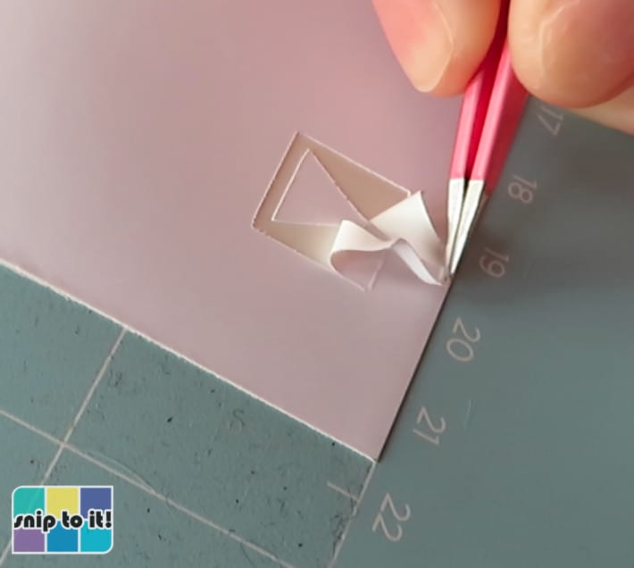 checking a test cut Orajet 1917 sticker sheet, using tweezers to weed out the box around the triangle