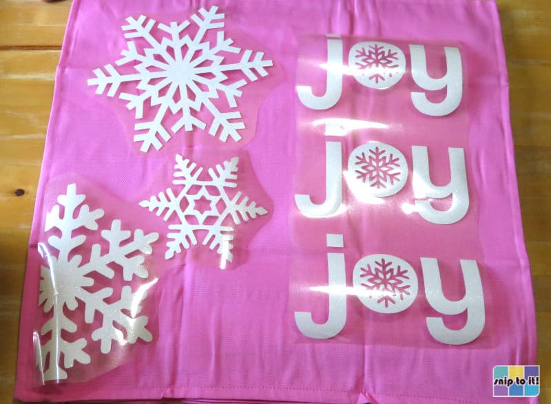 joy joy joy white glitter design pieces arranged on pink pillowcase before pressing