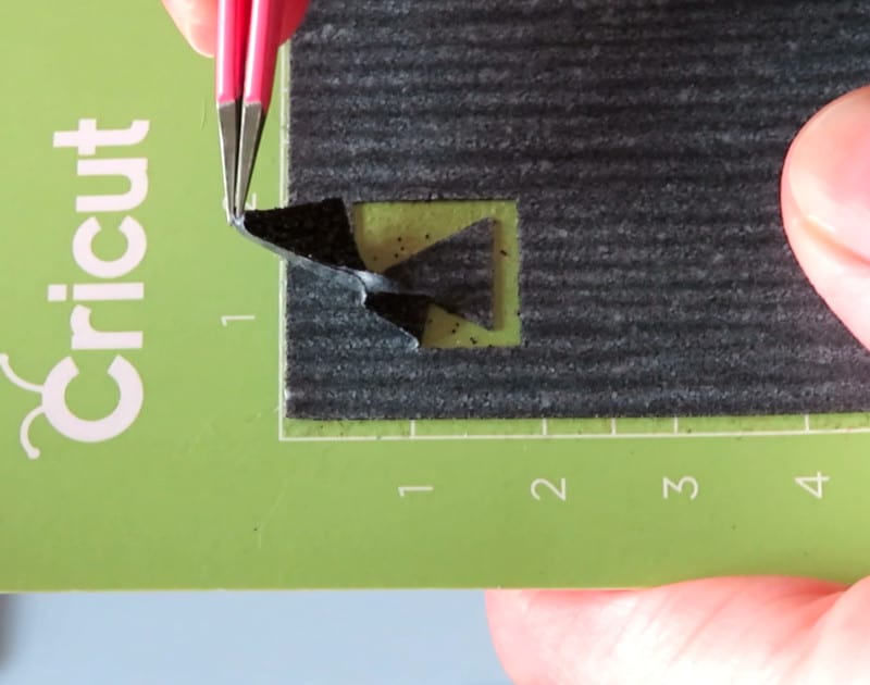 black glitter HTV on cutting mat showing weeding of test cut triangle