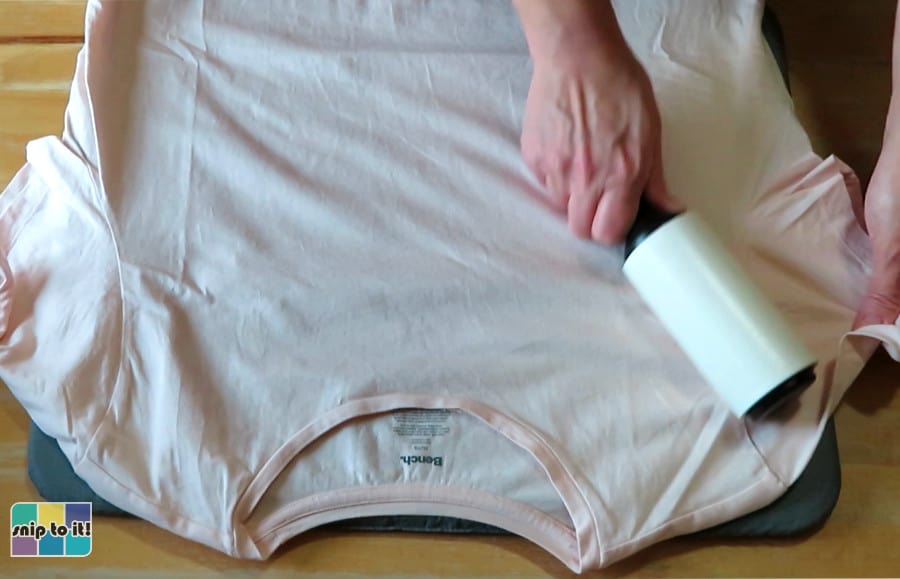 lint roller being used to remove debris from pink women's t-shirt