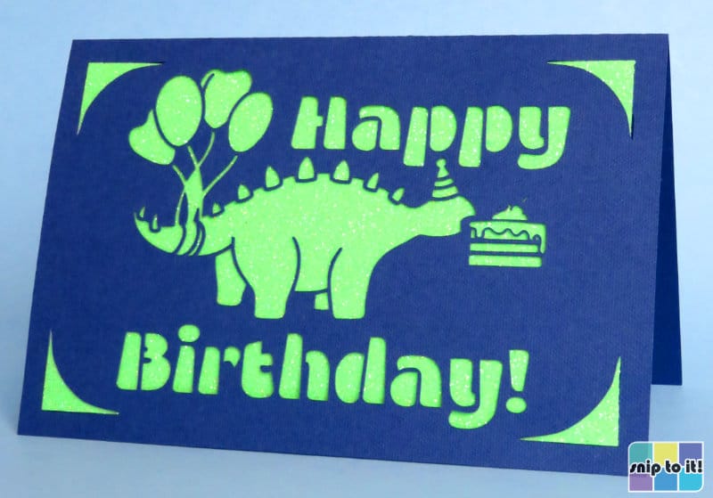 cricut insert birthday card made using dinosaur image + Balladon retro stencil font cut out of dark blue cardstock with a neon green glitter insert
