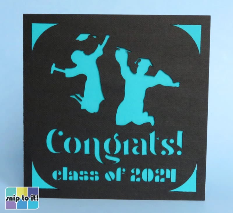 cricut insert grad card made using image of graduates + Wangi and Densmore stencil fonts cut out of black cardstock with a light blue insert
