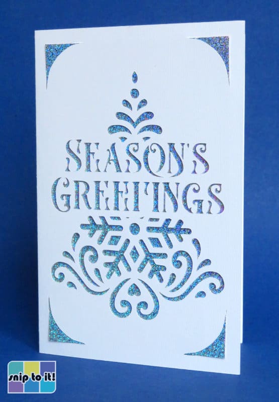 cricut insert christmas card made using stencil christmas tree + Albrega Changes elegant stencil font cut out of white cardstock with a holographic blue insert