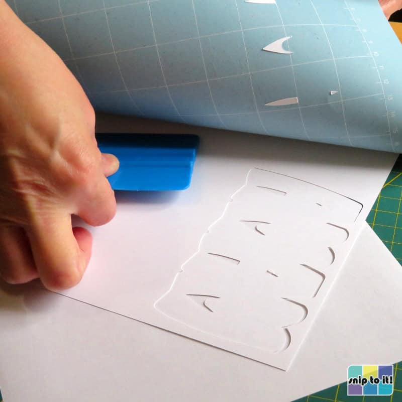 photo of correct way to remove cardstock from cutting mat, flipping mat over and removing the white cardstock layer with a squeegee/scraper