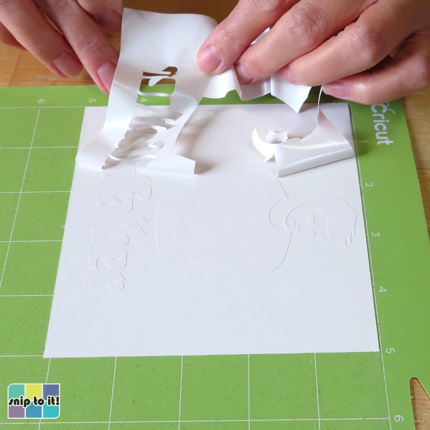 closeup image of excess adhesive vinyl being weeded away from a cut design