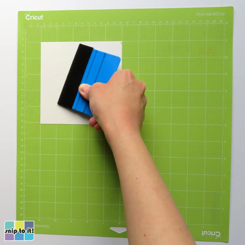 closeup image of adhesive vinyl applied to a cricut mat with a felted squeegee