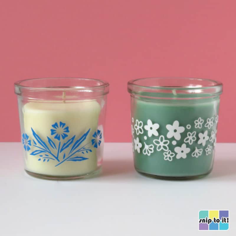 photo of white votive candle with blue vinyl decoration in vintage corningware cornflower pattern, next to green votive candle decorated with white vinyl in pyrex spring blossom pattern