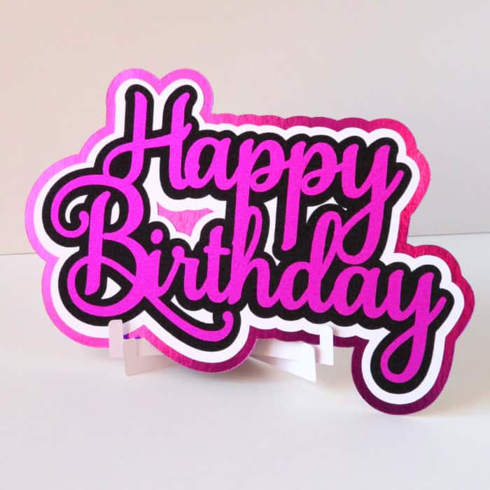 image of a finished cake topper made with multiple layers of cardstock and vinyl. The contour tool has been used to remove small cuts between letters in the first offset layer under the text.
