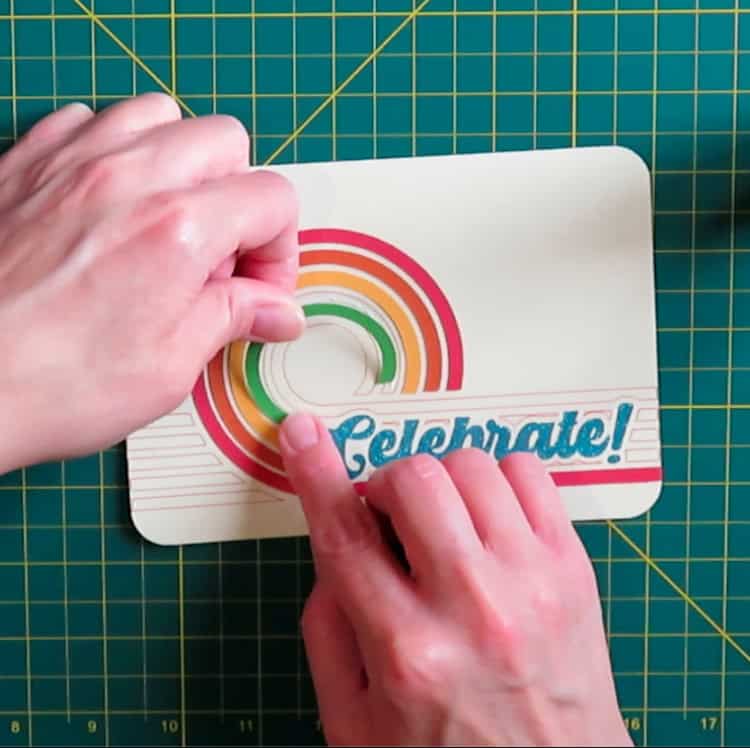 photo showing construction of retro birthday card. glue is added to base panel within drawn guidelines, then cardstock design elements are placed on the glue layer