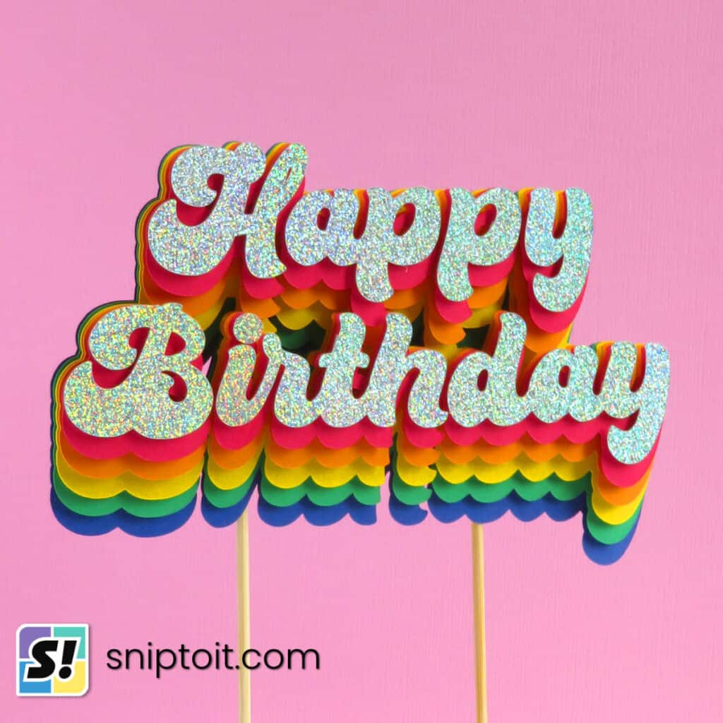 closeup photo of a layered cardstock birthday cake topper featuring a rainbow text effect