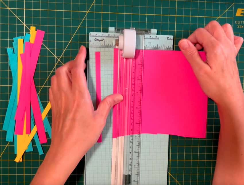 photo of a paper trimmer being used to cut 1/4" and 1/2" strips of colored cardstock to make a custom striped panel