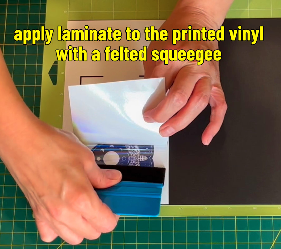 photo of applying holographic laminate sheet overtop of printed vinyl mounted on heavy cardstock