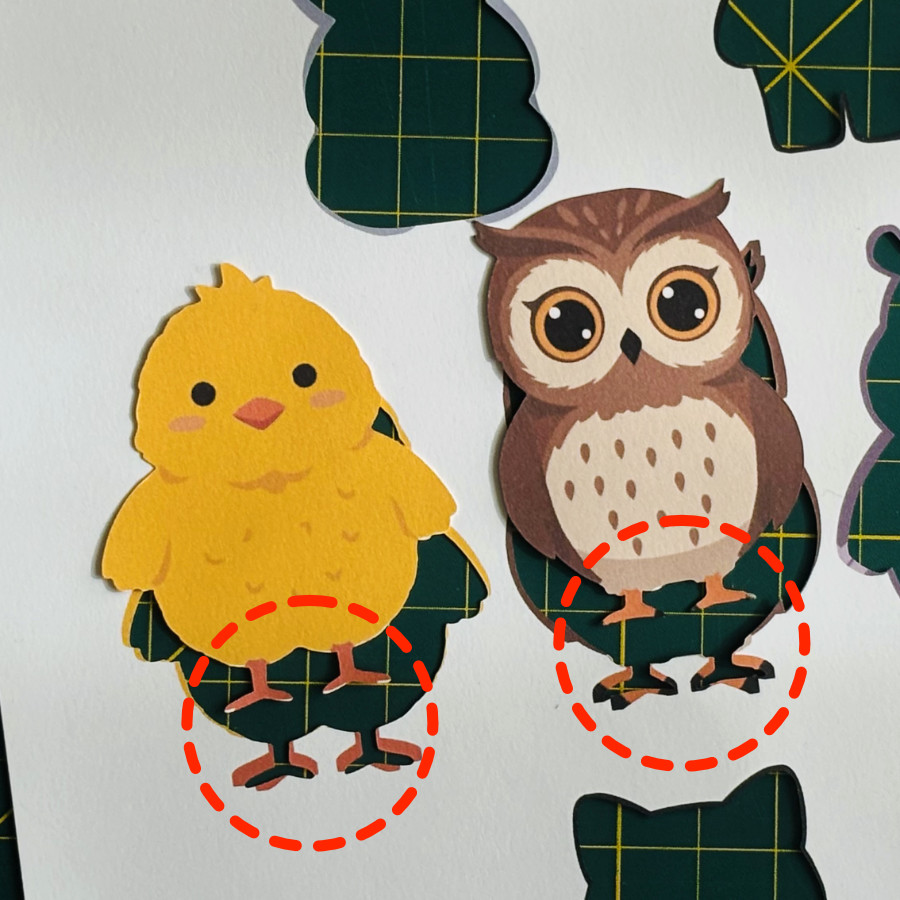 closeup of cardstock owl and chick showing mismatch of front and back foot print and cut. Images were cut using the back cut line, which removed some toe details from the front of the images