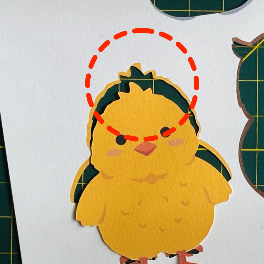 finished double-sided print then cut cardstock chick showing small mismatch in front and back images. top feathers point in different directions in the front and back images and the back cut line was used, but the print bleed covers up the small mistake