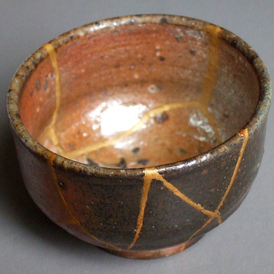 ceramic bowl repaired via kintsugi technique, showing gold seams where the breaks were