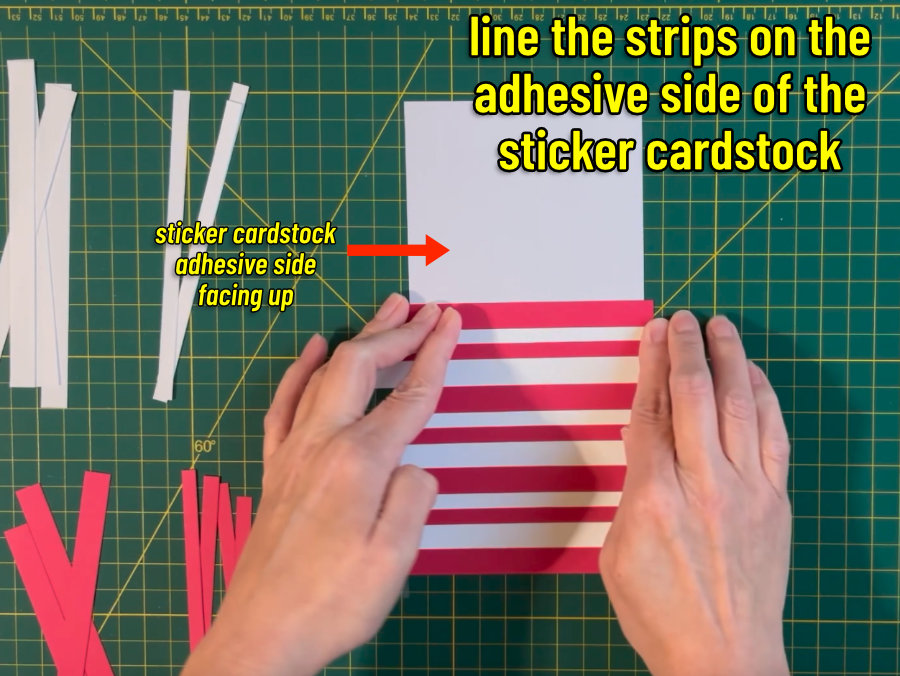 red and white strips of cardstock being arranged on the adhesive side of a rectangle of sticker cardstock