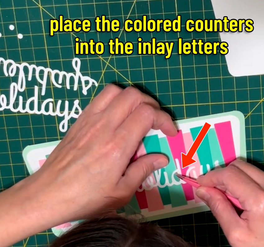 closeup image of the colored cardstock counters (the empty space inside a letter, like the open hole in d or D) filling in the open spaces in the white inlay text on the front of the inlay christmas card