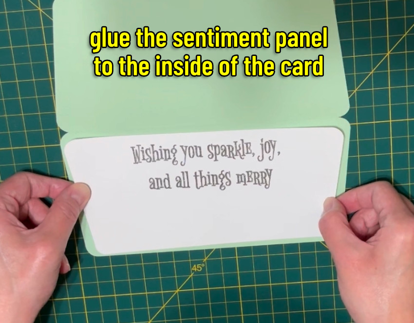Closeup image of the sentiment panel with the text "Wishing you sparkle, joy and all things merry" being glued inside the mcm christmas inlay card