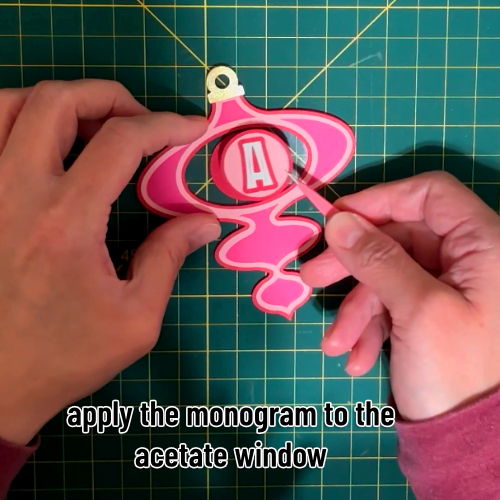 the finished monogram layers are adhered to the acetate window using tape runner