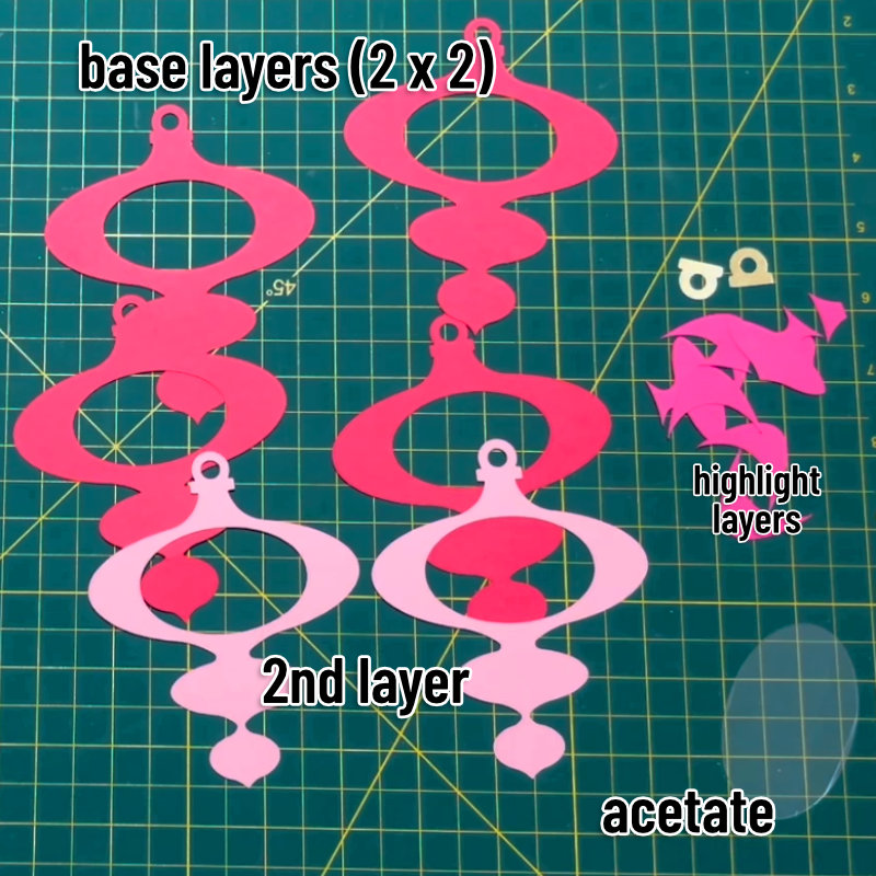 all of the cut layers of pink cardstock prior to assembly of the christmas ornament. Each group is labeled to indicate their layer order