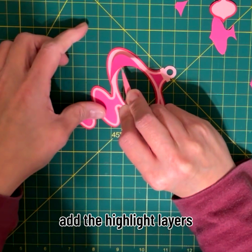 the small highlight layers of cardstock being applied to the base layers with a pair of tweezers