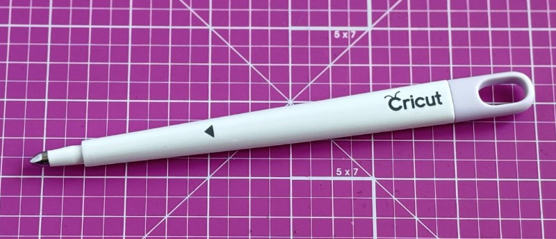 closeup image of the Cricut scoring stylus on a pink cutting mat