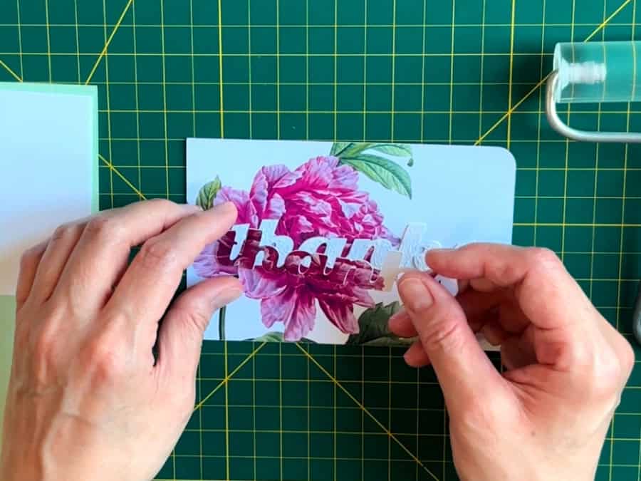 photo showing the final step in assembling the front of the eclipse card. The top printed layer of text is glued onto the 3 spacer text layers that have already been glued onto the base panel.